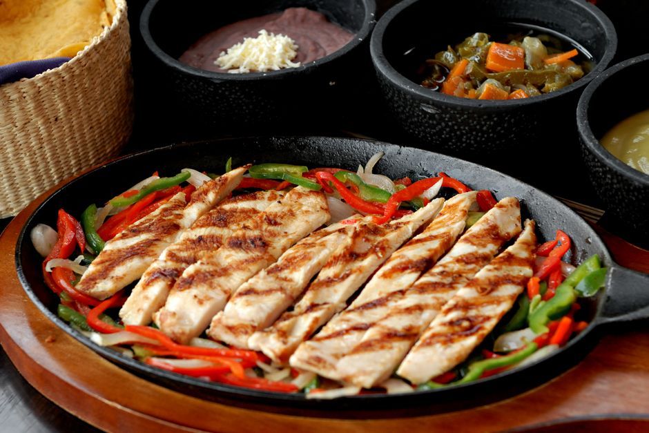 Fajitas — Grilled strips of meat and peppers, served to assemble at the table.